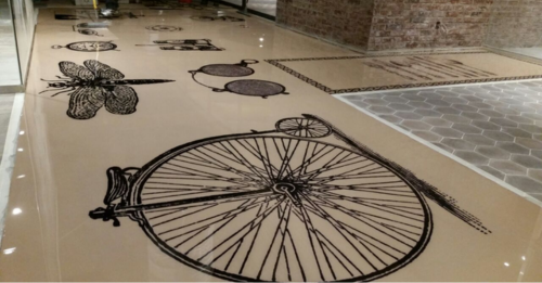 How is it done? Your objects or graphics are embedded within the layers of resin, ensuring it remains intact and vibrant over time, even in high-traffic areas. Thinking about this personalized approach? Learn about Capture flooring.